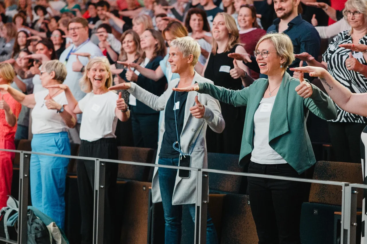 Teilnehmende einer Kita-Veranstaltung bewegen sich gemeinsam im Publikum.